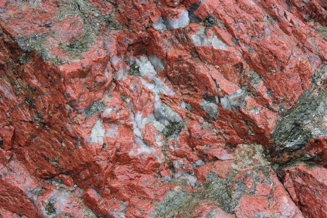 Nedenunder ses både den røde feldspat og linser af ren kvarts samt rester af endnu uomdannet gnejs.
