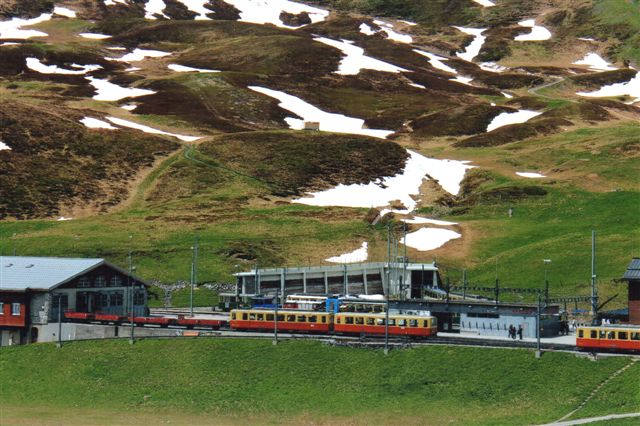 To af de ældre togsæt ved remisen. Hele gedemarkedet på Jungfraujoch  skulle forsynes med alt lige fra mad, souvenirs og drikkevand med banen. Disse tog fremførste normalt af de ældre motorvogne. Det anderledes farvede materiel er WABs. Mundingern til vendetrekanten inde i bjerget ses. Del skulle maskinen være nederst på faldet, og dels var sæderne indrettet med rygstøddets hældning til kun at køre på en bjergside. Der var vendetrekant i Grund og her i Kleine Scheidegg. 2012.
