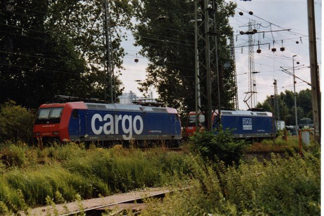 SBB 9 447. SBB Cargo 482 018-9 på Hamborgs Havn 2005. Lokomotivet holder sammen med et RAG 224 (Ruhrkohle AG) på havnebanegården Hohe Schaar i bydelen Wilhelmsburg. RAG-maskinen er i øvrigt også et SBB-lokomotiv lejet af RAG.