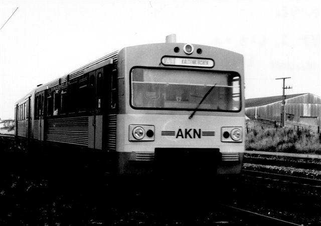 AKN VT2.31 krydser orlovstoget i Boostedt 1986. Disse moderne togsæt kørte sjældent nord for Kaltenkirchen, men som det ses her, hændte det. Formentlig var toget udstyret med både el og diesel. På det første stykke af banen i Hamburg kørte S-banen og AKN på samme spor med tredjeskinne til strømforsyning. under et kort stop på vejen startedes dieselmotoren, og toget forstsatte uden strømskinne. 