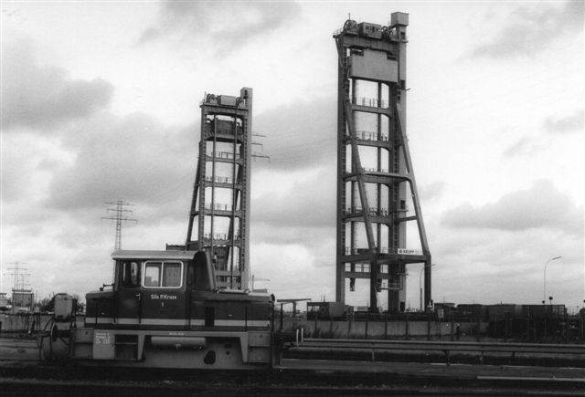 Kruse 1 med Rethebroen som baggrund. På havnen fandtes en del klapbroer og to hævebroer, hvor vej- og baneforløbet hævet ved hjælp af de to elevatortårne, så et skib kan passere under. 1986.