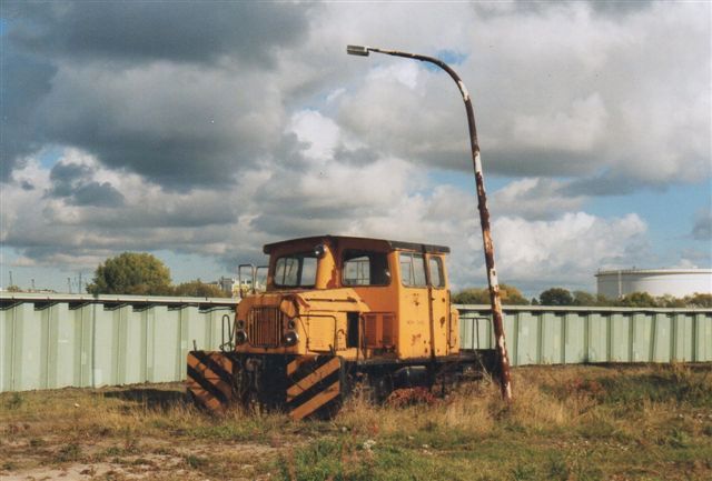 2003 stod lokomotivet ved HJM Hafenumschlagsbetriebe og så noget brugt ud. Fotografen Jochim Rosental har ikke angivet nogen adresse. Hegnet er en beskyttelsesmur mod højvande. 