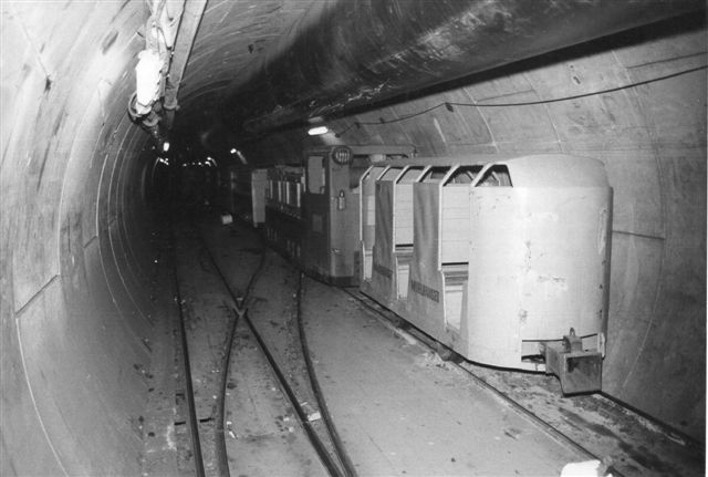 En mandskabsvogn og lokomotiv uden nr, SIG 709744/1979 sammen med andet materiel i tunnelen. Foto: Ulrich Völz 1986.