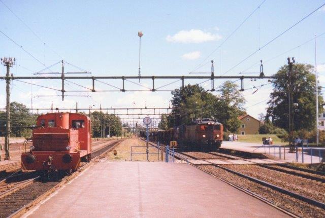 Vor maskine har krydset hovedsporene Stockholm - Göteborg og afventer nu rangertilladelse. Imens raser et godstog fremført af SJ Ma 873 genne stationen. 1986.